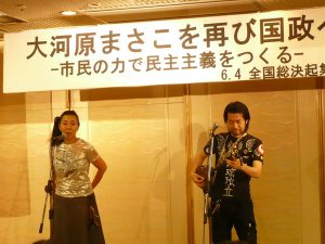 集会のオープニングは、琉球弧の島々で歌い継がれる島唄とオリジナルソングのライブ活動を国内、国外で展開している寿［kotobuki］の二人によるミニライブ。参加者も声をあわせて、にぎやかな開会をなった