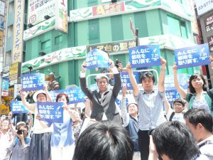 応援に集まったおおぜいの市民とともに、「みんなに都政を取り戻す。」のスローガンパネルを掲げる鳥越俊太郎さん。7月14日